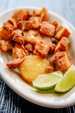 Colombian fried pork belly chicharrn colombiano with sliced limes clipart