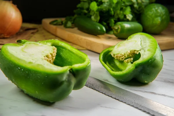 Green bell pepper sliced in half showing seeds and pith