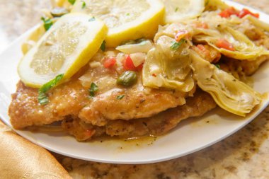 İtalyan tavuklu piccata şnitzel ve fettuccine ile servis edilen enginar kalbi.