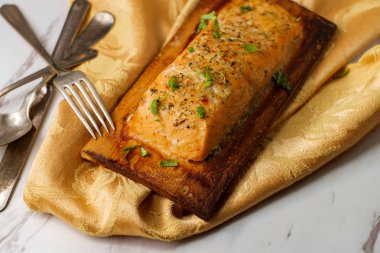 Sedir ağacında servis edilen turunçgil ve otla tatlandırılmış taze ızgara somon.