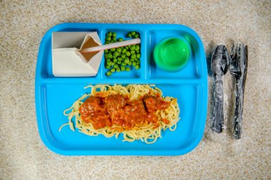 İlkokul öğle yemeği tepsisi İtalyan spagettisi ve yeşil bezelye sütü ve jelatin kaplı köfte.