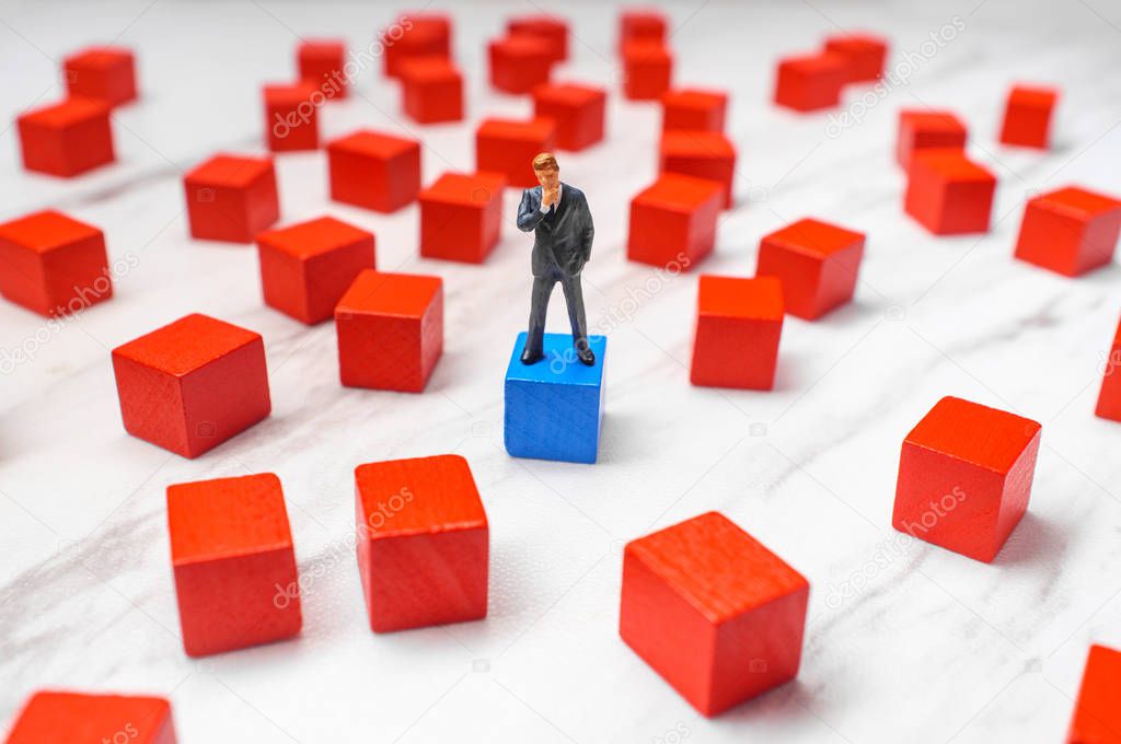 Miniature businessmen surrounded by wooden blocks representing possible choices and solutions to problem