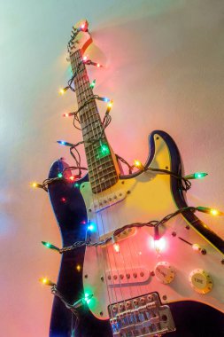 Seasonal holiday musical instrument electric guitar wrapped in Christmas tree string lights clipart