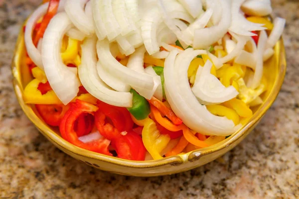 Chopped yellow onion with red green and yellow bell peppers for cooking with sausage recipe