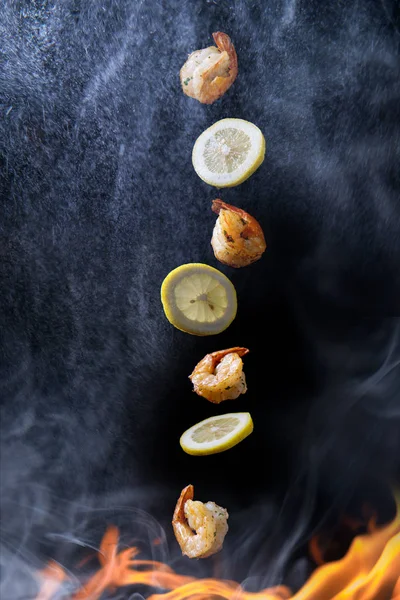Stir frying and tossing shrimp with sliced lemon concept with steam smoke and flames
