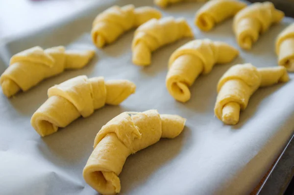 Raw croissant roll dough on parchment paper and pan ready for the oven