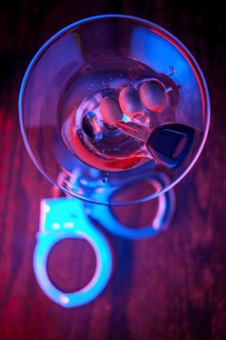 Elleri kelepçeli ve anahtarlı cin martini, alkollü araç kullanmanın sembolü. 