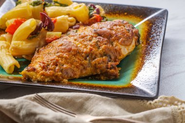 Güneşte kurutulmuş domates kırmızı pesto mozzarella peyniri ve sarımsak parmesan Roma rigatoni rigati bir tarafı ile Yunan hasselback tavuk 