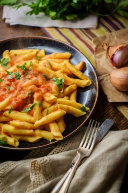 Kırsal ahşap mutfak masasında kremalı votka soslu makarna.