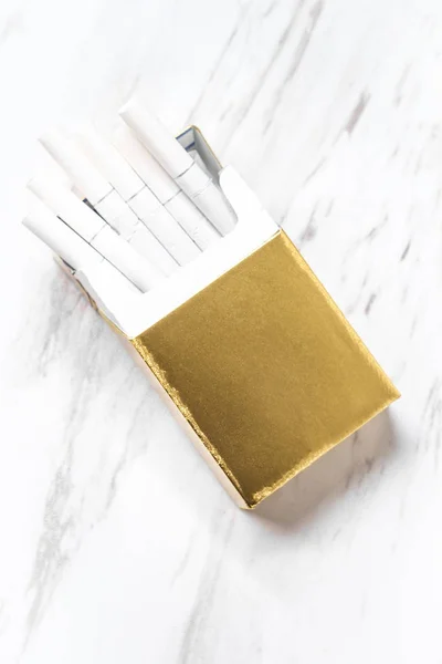 Open half empty gold pack of cigarettes on marble kitchen table