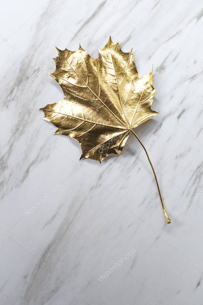 Golden Christmas maple leaf on marble table in closeup