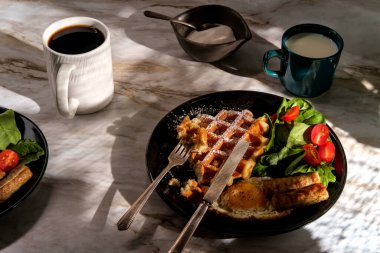 Sosisli yumurta ve kahveyle servis edilen Belçika waffle kahvaltısı.