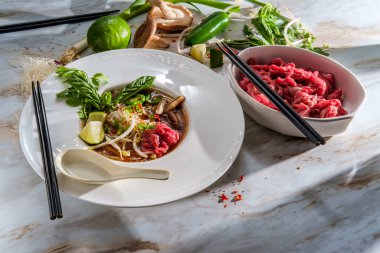 Geleneksel Vietnamlı pho bo biftekli şehriye çorbası fesleğenli kişniş mantarı ve fasulye filizi ile servis edilir.