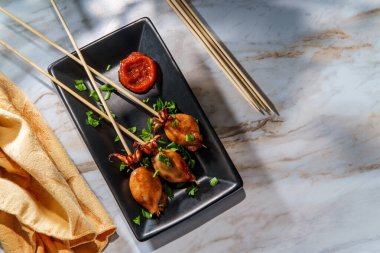 Deniz ürünleri ızgara kalamar satay kebap, dokunaçlı şiş ve acı sos.