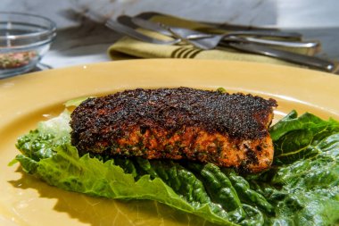 Cajun cuisine blackened salmon steak on marble kitchen table clipart
