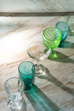 Mermer mutfak masasında çeşitli şekillerde içki bardakları var.