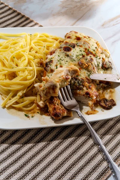 Italian cuisine chicken Lombardy with marsala mushroom gravy and linguine