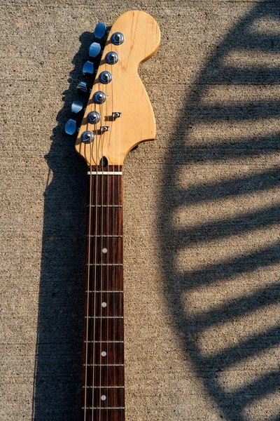 电吉他颈放在人行道上 有强烈的阳光阴影供戏剧化 — 图库照片