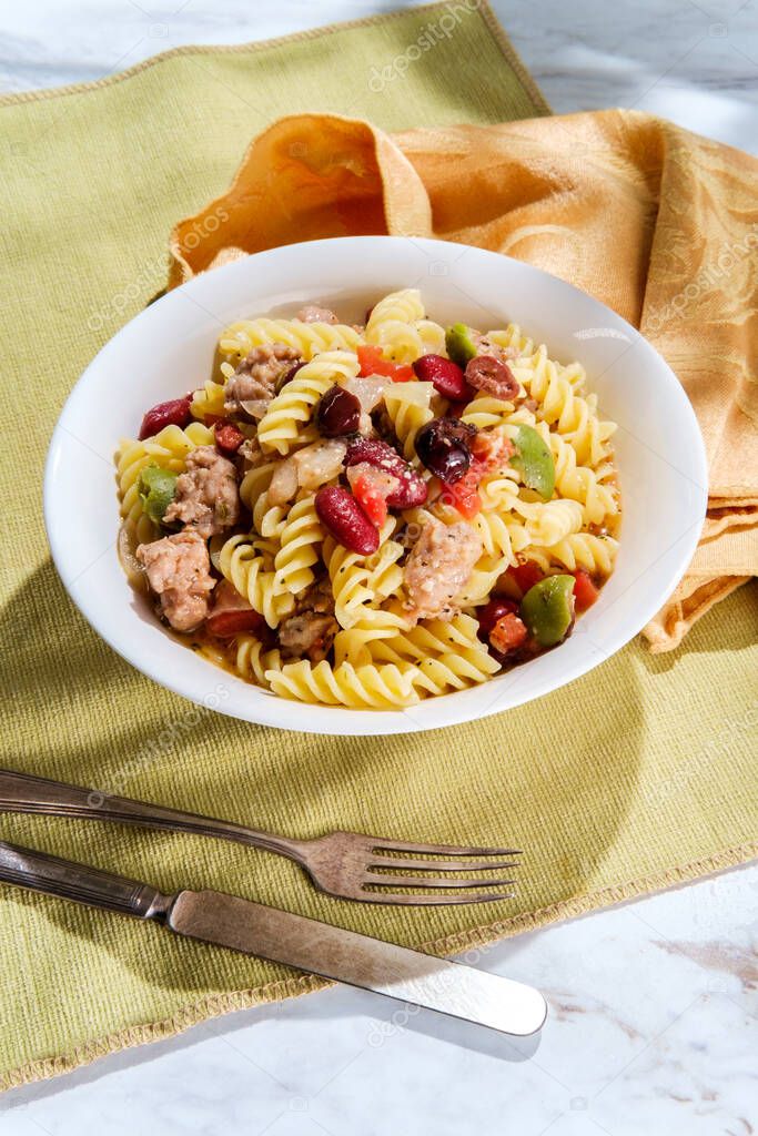 Italian sausage rotini pasta with castelvetrano and kalamata olives and kidney beans in a light tomato white-wine butter sauce