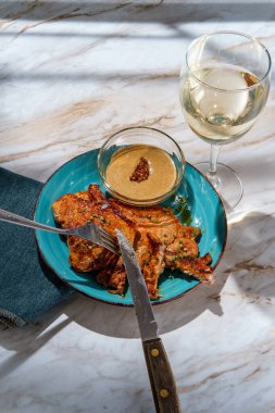 Kızarmış domuz pirzolası, ballı hardal sosu ve bir bardak beyaz şarap.