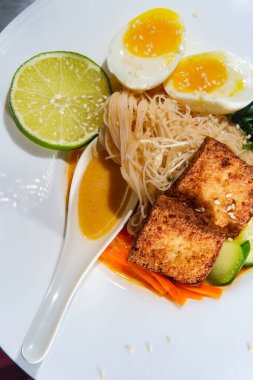 Tayland usulü vejetaryen körili pirinç çorbası yanında kızarmış tofu ve haşlanmış yumurta.