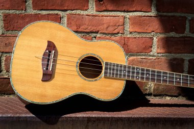 Akustik bariton ukulele gitar, tuğla duvara karşı, konser salonunun dışında kaldı.