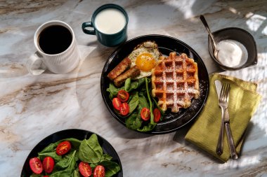 Sosisli yumurta ve kahveyle servis edilen Belçika waffle kahvaltısı.