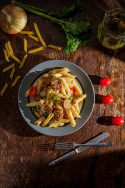 İtalyan baharatlı sosisli makarna ve pencereden çarpıcı ışık saçan brokoli haham.