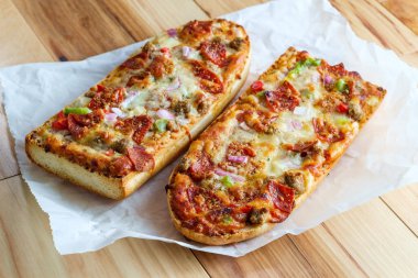 Biberli, sosisli, siyah zeytinli, kırmızı soğanlı ve yeşil biberli Yüce Fransız ekmeği pizzası.