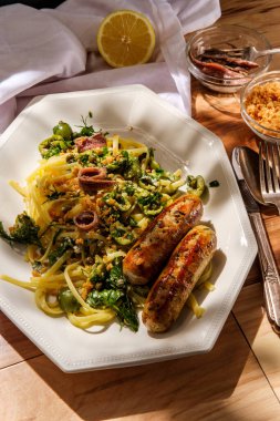 İtalyan tavuğu ıspanak sosisi ve linguine ile yeşil kastelvetrano zeytin sosu ile süslenmiş çıtır ekmek kırıntıları.