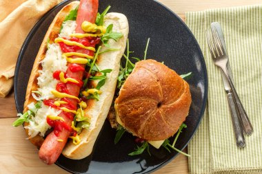 Peynirli hamburger, kepekli çörek, üstüne sosisli ve lahana turşusu. 