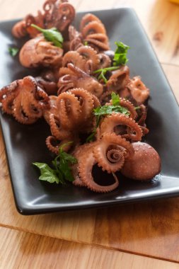Zeytin yağı ve maydanozla servis edilen haşlanmış bebek ahtapot.