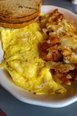 Peynirli yumurta omleti, patates kızartması ve kızarmış çavdar ekmeği.