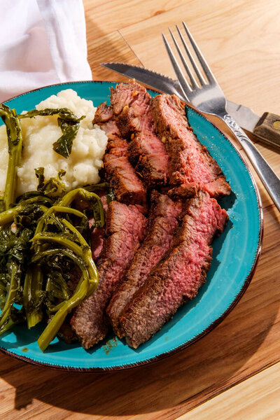 Medium rare steak dinner with mashed potatoes and broccolini 