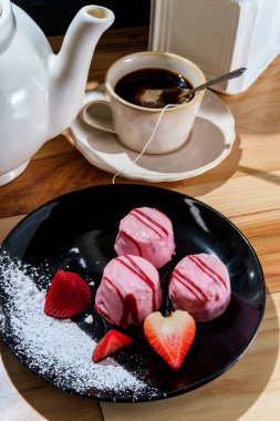 Çay fincanı ve demlik ile çilek kremalı çay kekleri.