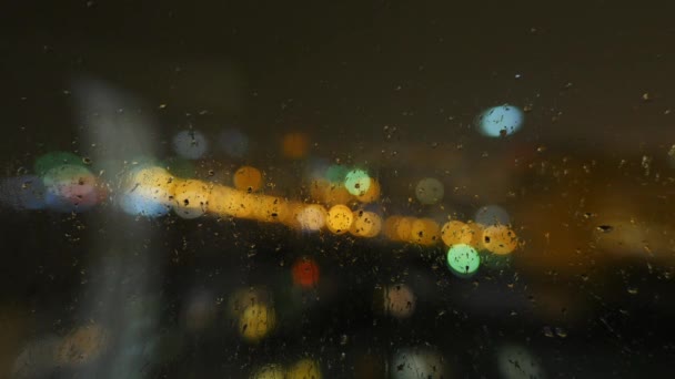 Imagen de gotas de lluvia en la ventana por la noche en la ciudad — Vídeo de stock