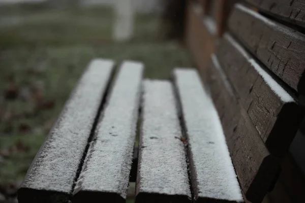 Banco na aldeia após a primeira neve, o fim do outono e o início do inverno — Fotografia de Stock