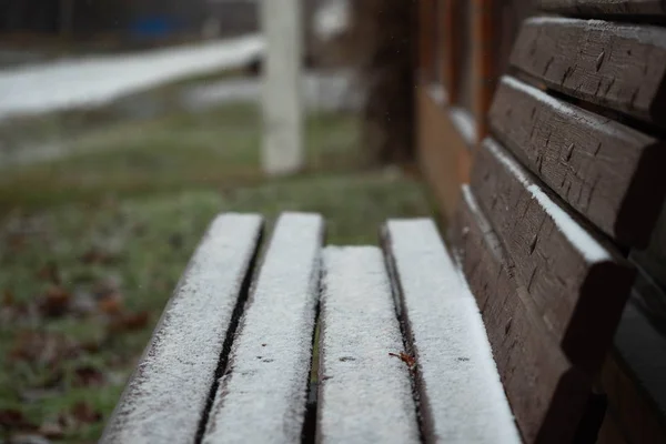 Banco en el pueblo después de la primera nieve, el final del otoño y el comienzo del invierno —  Fotos de Stock