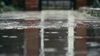 yağan yağmur damlaları kaldırıma su birikintileri düşmek. yakın çekim. Ağır çekim. 4k