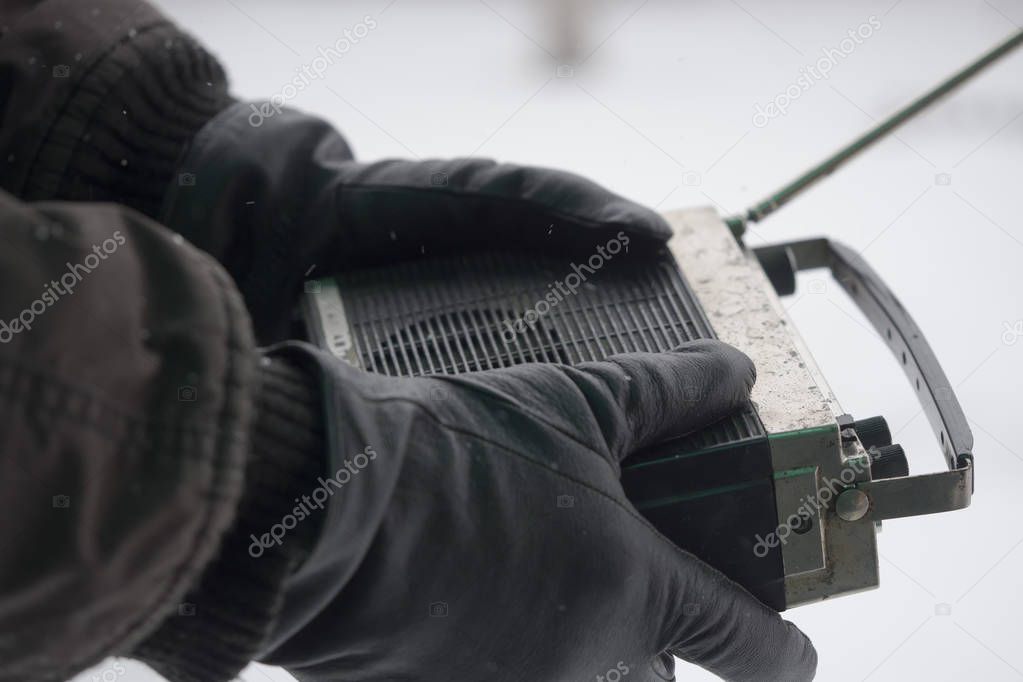 man in winter gloves is holding an old radio. Search for lost winter tourists concept