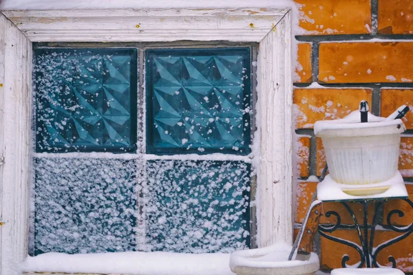 Ventana texturizada de un cobertizo de ladrillo barrido por la nieve junto a una maceta vacía —  Fotos de Stock