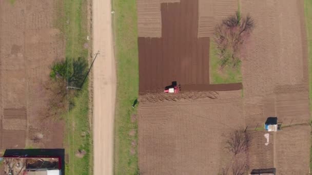 Küçük bir traktör bir dron farklı açılardan çekim köyde arazi pulluklar. Sürülmüş sezonu erken Bahar, sebze Ekim başında — Stok video