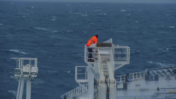 Kargo vincindeki bir gemide tehlikeli koşullarda çalışmak. Kot ceketli bir adam ve petrol tankerinde bir yük vanı. — Stok video
