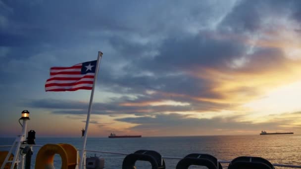 Bandeira da Libéria Acenando ao vento, Céu, Fundo do Sol e fundo das embarcações — Vídeo de Stock