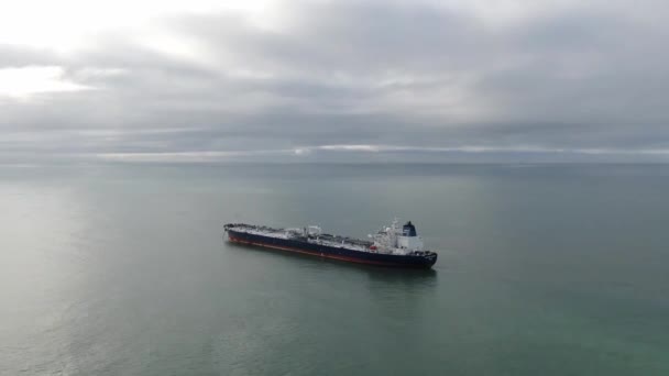 Vista aérea anclaje buque de carga en la zona de anclaje. Drone volando sobre el agua mostrando el paisaje marino en día nublado, alrededor del petrolero solitario en ancla — Vídeos de Stock