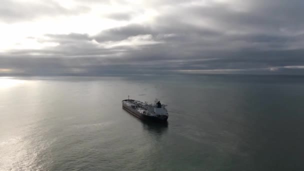 Vista aérea anclaje buque de carga en la zona de anclaje. Drone volando sobre el agua mostrando el paisaje marino en día nublado, alrededor del petrolero solitario en ancla — Vídeos de Stock