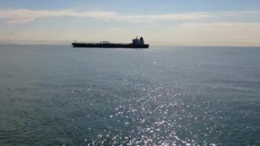 Anchorage bölgesinde hava görüntüleme tankeri demirliyor. Suyun üzerinde uçan drone bulutlu bir günde deniz manzarası gösteriyor, kamera güneşli bir günde yalnız tankerlere doğru hareket ediyor.
