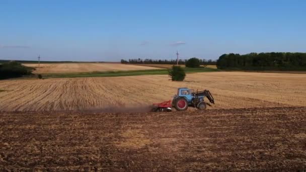 Lezoucí traktor obdělává půdu na zemědělském poli. Boční pohled na dron — Stock video