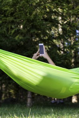 bir hamakta rahatlatıcı ve cep telefonunu kullanarak kadın