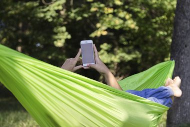 kadın bir hamakta bir cep telefonu kullanıyor